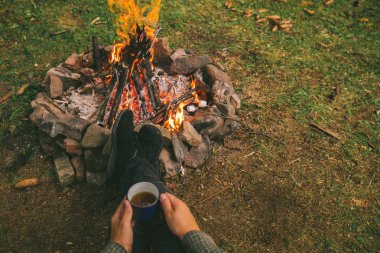 ilk bakış. kamp ateşi yakınındaki metal fincan çay içme adam. Hiking