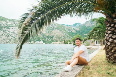 deniz kenarında güzel görünümü ile oturan adam. arka planda dağlar. Yaz saati