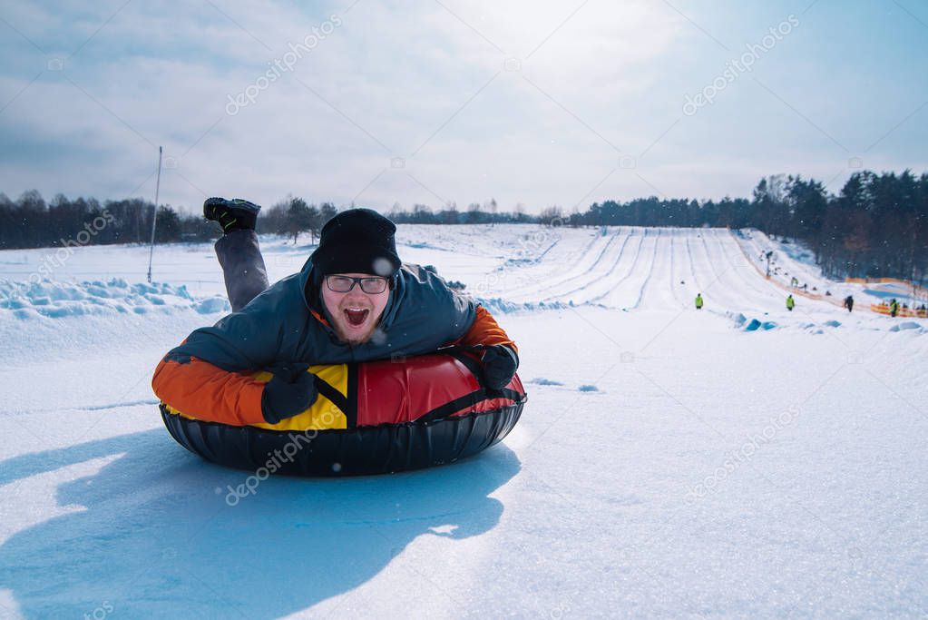 man snow tubing from hill. winter activity concept