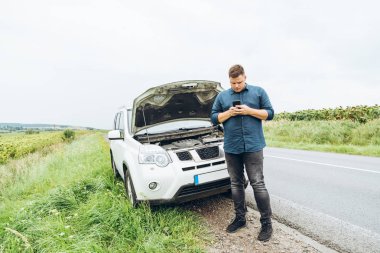adam telefonu ile kırık araba önünde dur. hiçbir yerin ortasında kırık