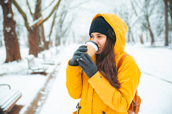 woman drinking coffee outside in park portrait. drink to go. winter time. warm up concept