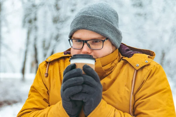 強力な笑みを浮かべて男コーヒーを飲むに雪が降った都市公園コンセプトで行くの肖像画 — ストック写真