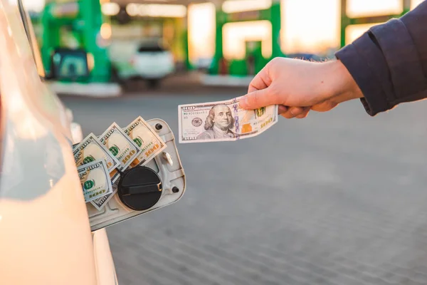 man hand puts money in car tank. car refueling. gas station concept