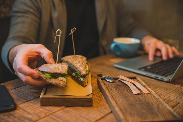Hombre Tomando Sándwich Cafetería Trabajando Con Ordenador Portátil Cerca Concepto — Foto de Stock