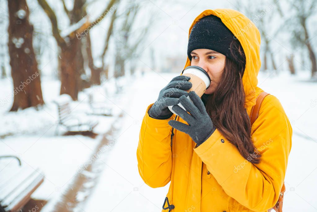 woman drinking coffee outside in park portrait. drink to go. winter time. warm up concept