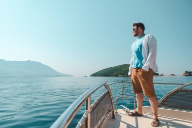 burun arka plan üzerinde deniz ve dağlar ile teknenin, ayakta başarı adam. yaz tatili