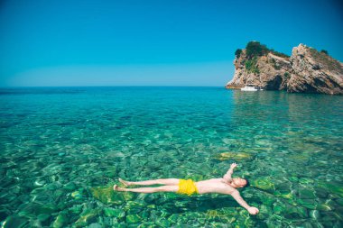 adam arka şeffaf açık suda ıslatın ve kayalık alt döşeme. yaz tatili