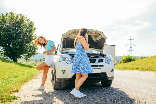 Dos mujeres al borde de la carretera llamando al servicio de autos. coche roto — Foto de Stock