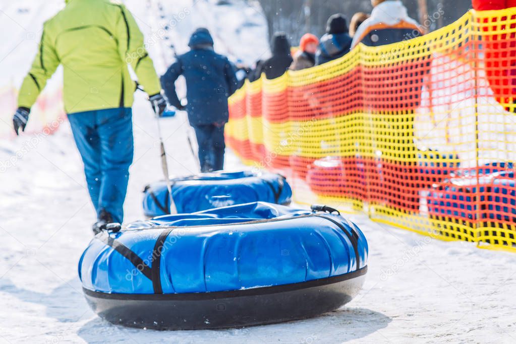 people in line to ride from snow hill. snow tubing. winter activity concept