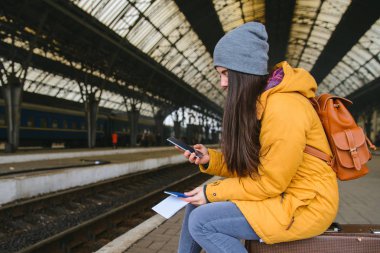 Trenin tren istasyonunda bekleyen genç güzel kadın. oturmak 