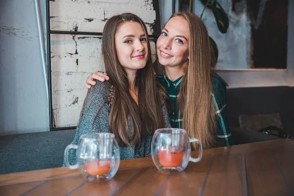 Couple girlfriends having fun sitting in cafe drinking fruit tea — Stock Photo, Image