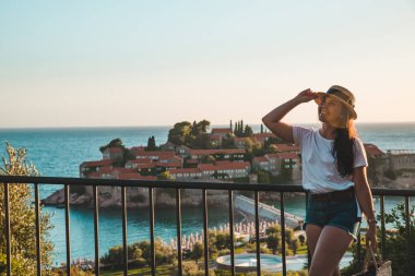 günbatımı üzerinde yürüyen Genç Yetişkin kadın. Sveti stefan Adası arka plan üzerinde. yaz tatili