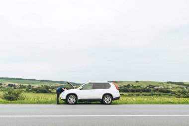 adam ayakta kırık araba ile açılan kukuleta yakınındaki. Acil servis. başarısız bir yolculuk