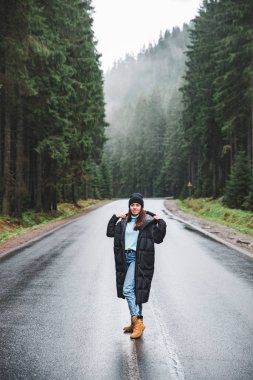 Kış dağlar ormandaki yolun ortasında duran genç kadın. seyahat kavramı