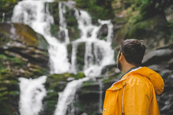 Mann Steht Gelbem Regenmantel Und Blickt Auf Wasserfall Wanderkonzept — Stockfoto