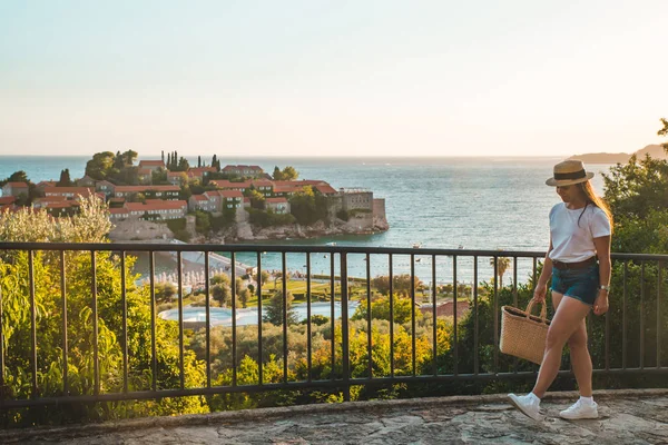 günbatımı üzerinde yürüyen Genç Yetişkin kadın. Sveti stefan Adası arka plan üzerinde
