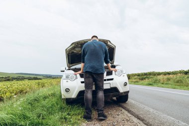 yol kenarında, kırık araba motoru bakarak adam. Road trip sorunları