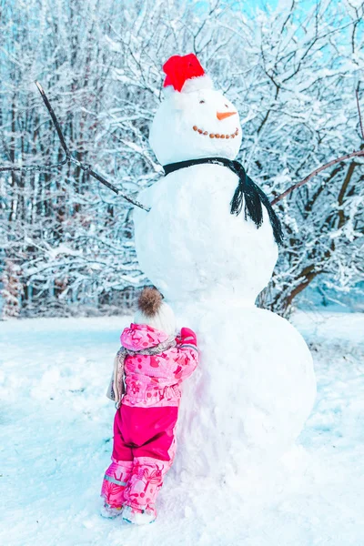 Kleines Vergoldetes Kind Pinkfarbener Winterkleidung Das Den Großen Schneemann Betrachtet — Stockfoto