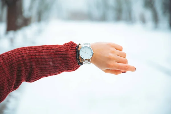 woman hand with watch on wrist winter snowed park on background concept