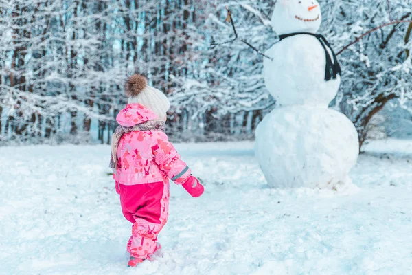 Klein Gild Kind Roze Winterkleren Kijken Naar Grote Sneeuwpop Wintertijd — Stockfoto