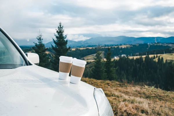 Auto Zblízka Dvěma Šálky Kávy Kapotu Horami Pozadí Cestování Autem — Stock fotografie