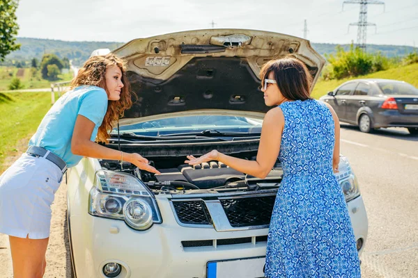 two women at roadside need help with broken car. car travel