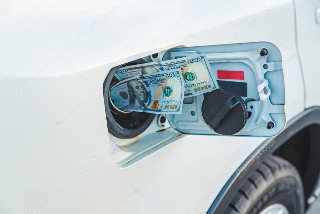 money in car tank close up. gas station refueling concept