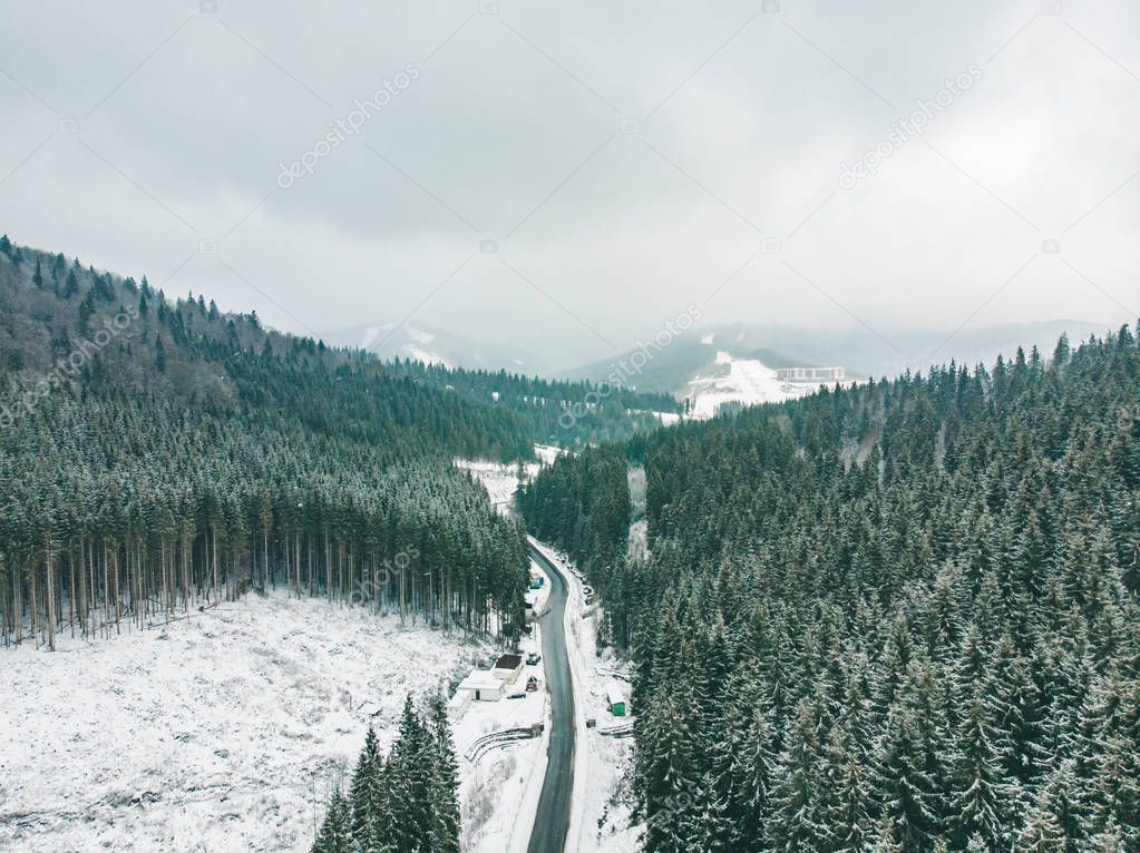 aerial view highway road in mountains range. snow storm. overcast. winter time