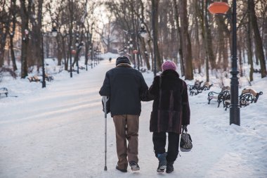 Kış city park ile birlikte yürüyen yaşlı bir çift. birbirleri hakkında bakım