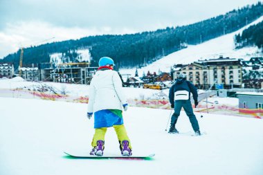 Erkek snowboard üzerinde renkli kostüm. arka plan dağlardaki kar yağdı. kış tatili