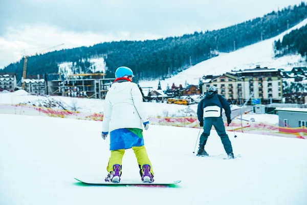 Erkek snowboard üzerinde renkli kostüm. arka plan dağlardaki kar yağdı. kış tatili