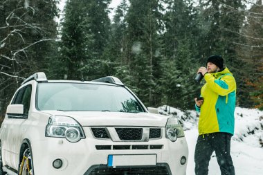 Zincir tekerlekler üzerinde suv yakınındaki ayakta adam. bir ara içki için çay sıcak ver. araba seyahat
