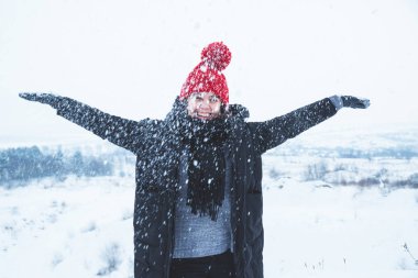 Açık havada kar ile oynayan kırmızı şapkalı kadın
