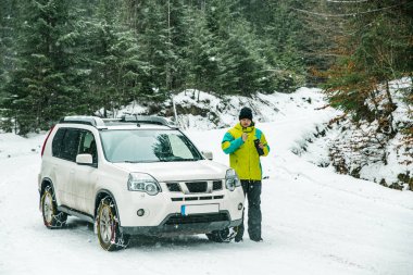Zincir tekerlekler üzerinde suv yakınındaki ayakta adam. bir ara içki için çay sıcak ver. araba seyahat