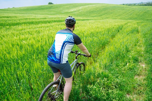 緑のフィールドで強力な若者乗馬自転車 — ストック写真