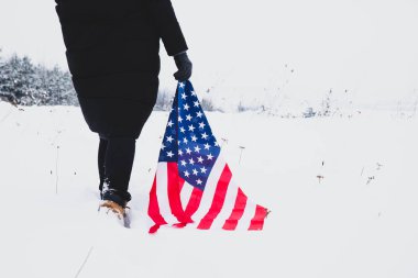 Kadın elinde ABD bayrağı ile karda yürüyordu. Kapat. Vatansever kavram