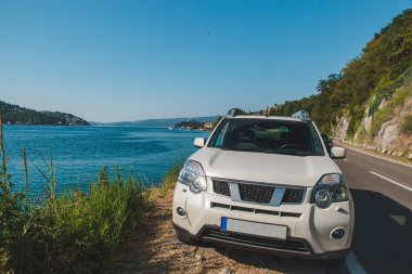 Beyaz jip araba Bay Dağları ile güzel manzaralı sahil Park. araba yolculuğu