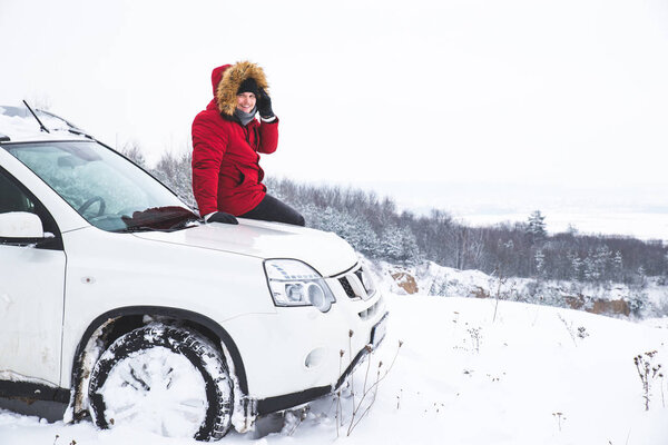 man traveler sitting on car hood with beautiful view of winter fields. lifestyle