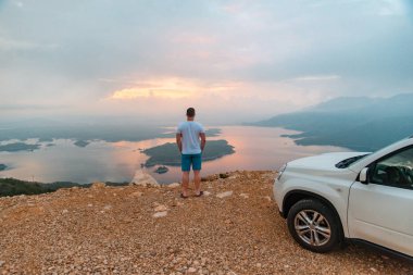 adam doğarken gölün seyir car yakınındaki uçurumdaki ayakta. yol gezi konsepti