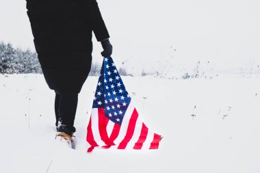 Kadın elinde ABD bayrağı ile karda yürüyordu. Kapat. Vatansever kavram