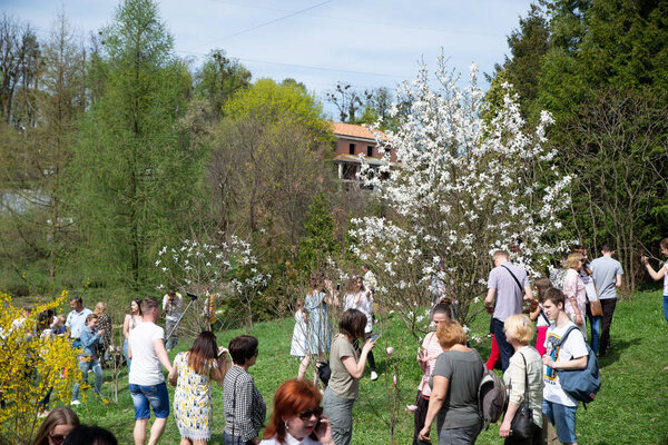 LVIV, UKRAINE - April 15, 2018: people walking by botanic garden looking blooming flowers. spring is coming