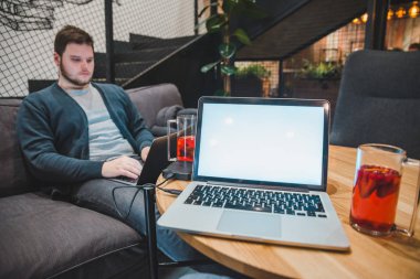 Cafe ahşap masa üzerinde beyaz ekranlı dizüstü bilgisayar. adam arka plan üzerinde çalışan dizüstü bilgisayar ile. kopya alanı