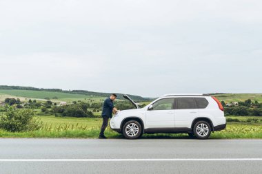 adam ayakta kırık araba ile açılan kukuleta yakınındaki. Acil servis. başarısız bir yolculuk
