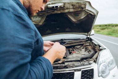 telefon elinde dostum. arka plan açılan kaputa. kırık araba