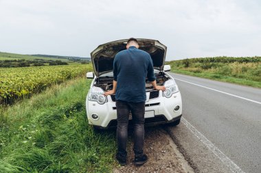 yol kenarında, kırık araba motoru bakarak adam. Road trip sorunları