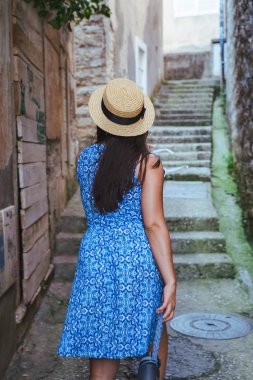 Herceg Novi küçük sokaklarında yürüyüş mavi elbiseli Genç güzel kadın. yaz tatil kavramı