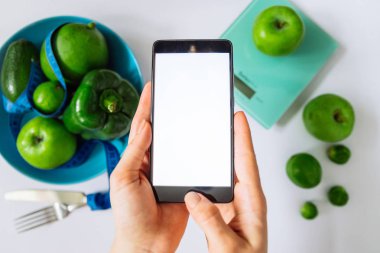 kadın bir şey cep telefonu seçin. sağlıklı gıda kavramı. kopya alanı.