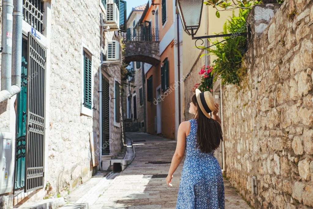 young pretty woman walking by tight european city streets. blue dress