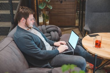 kafede dizüstü bilgisayarda çalışan adam. kulaklık ile müzik dinleme. beyaz ekran. kopya alanı