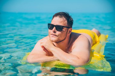 açık şeffaf su sarı şişme yatak, Genç adam. yaz tatil kavramı